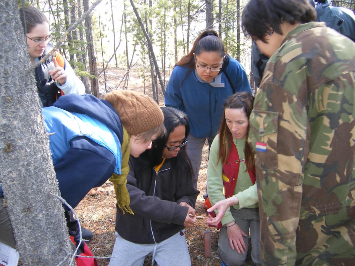 students in the field examining bark from a tree