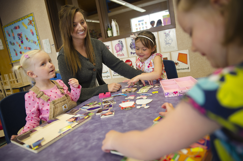 Early Learning Instructor sitting at table with 3 young children