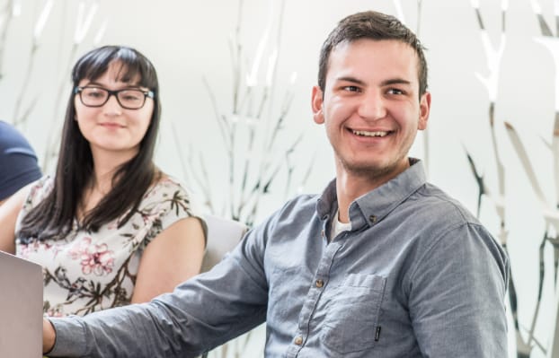 Two students sitting in a meeting room, smiling