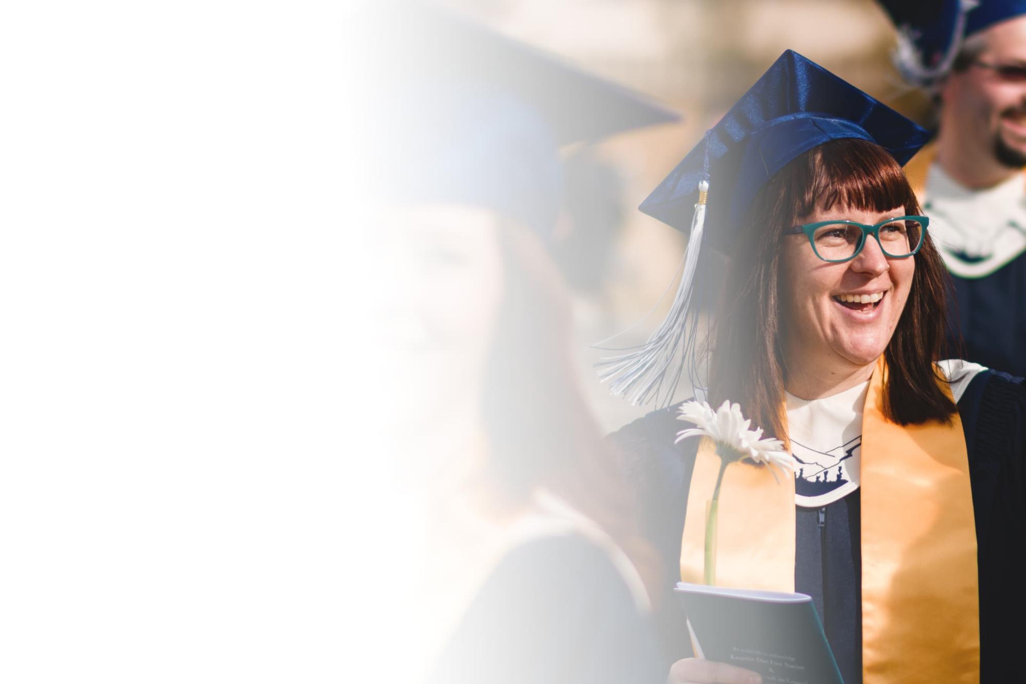 A student wearing grad regalia smiling during procession