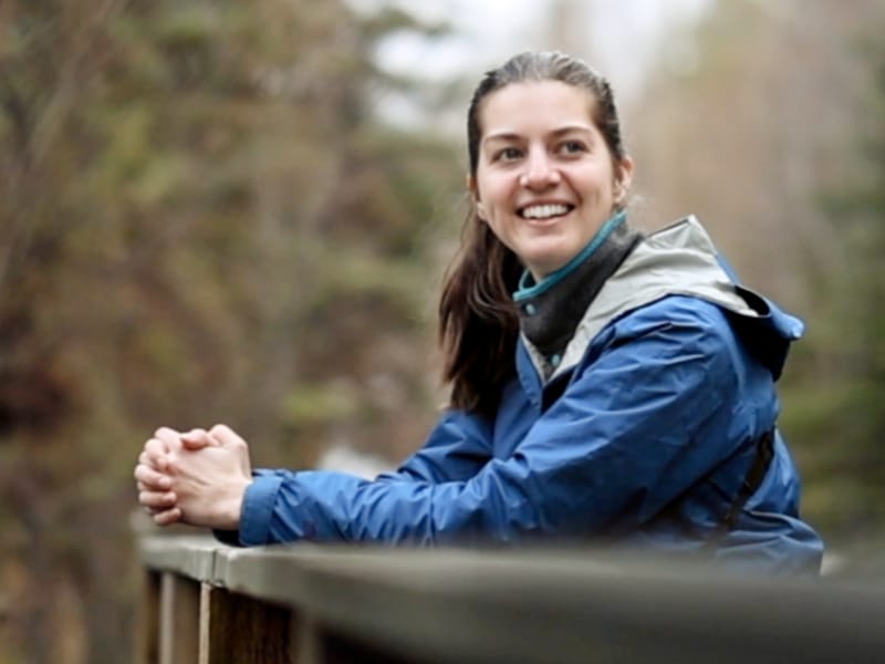 Woman in a blue jacket leaning on a railing