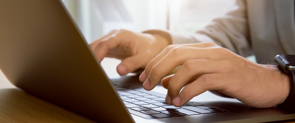 Hands typing on a laptop keyboard