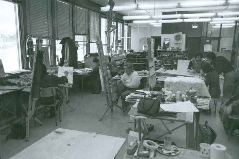 Black and white photo of a group of people seated at easels and painting