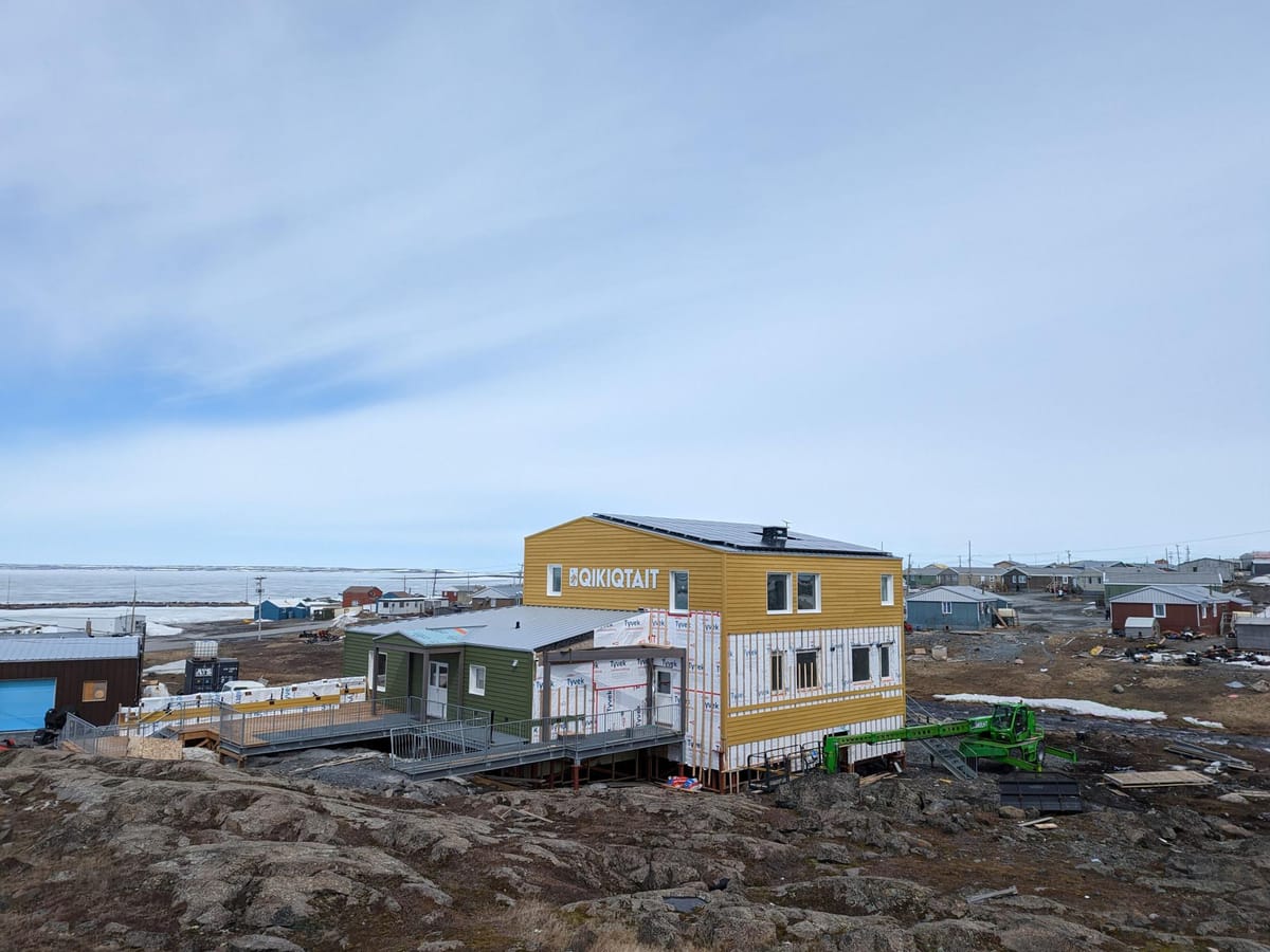 A building constructed on a rocky coast. Yellow siding is being installed on the building.
