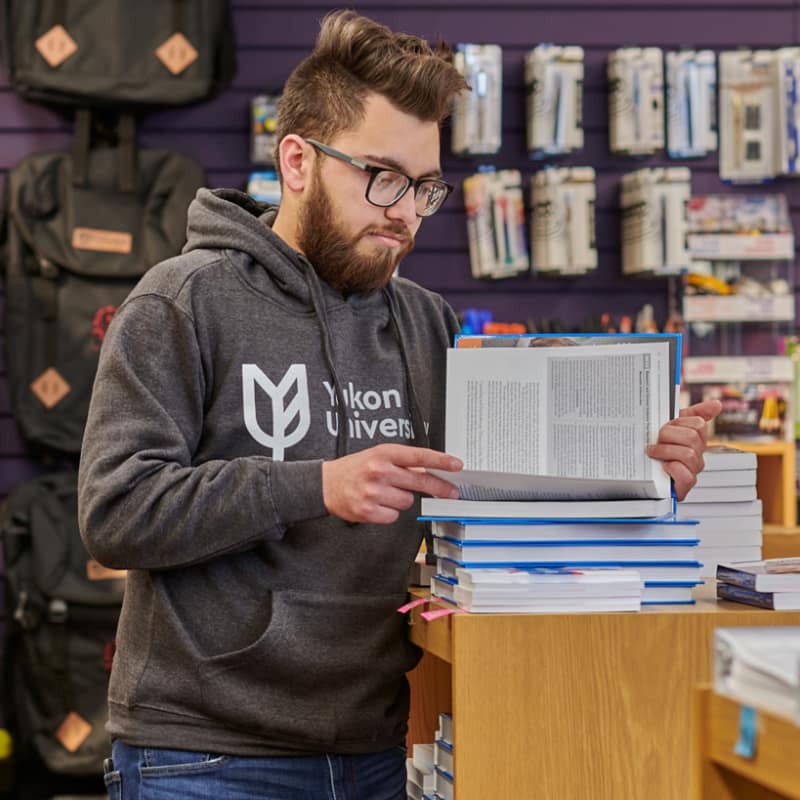 A student looks at an open text book in the campus store