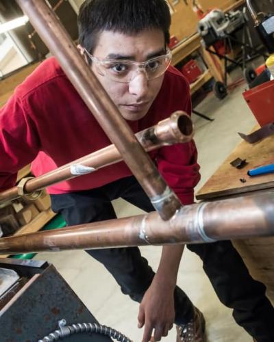 A pipe trades student working with copper pipe