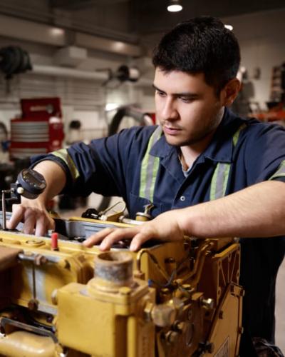 A heavy equipment technician student working on a piece of equipment