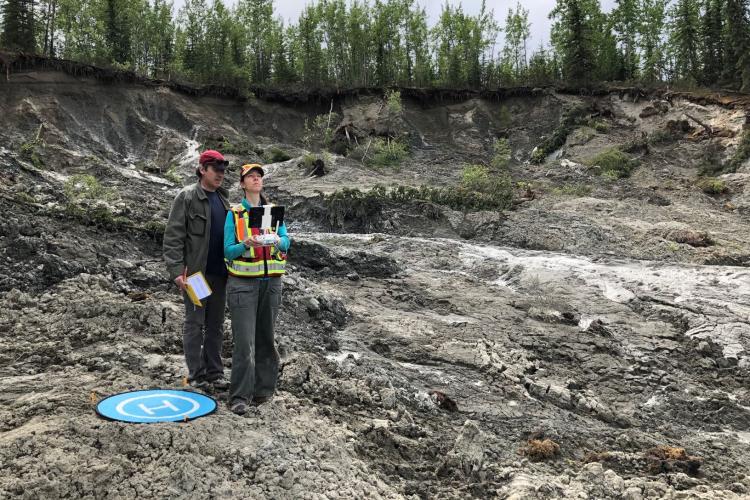 Two people operating a drone at a permafrost slump