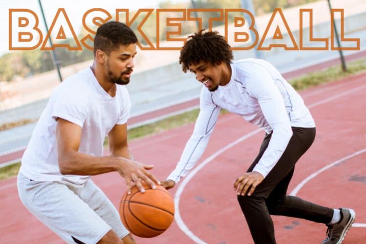 Two men in white shirts playing basketball on a red court