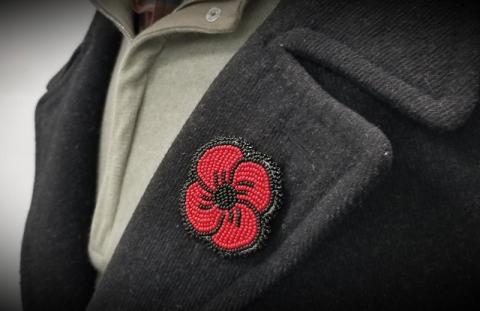 A beaded poppy on the lapel of a charcoal coloured coat