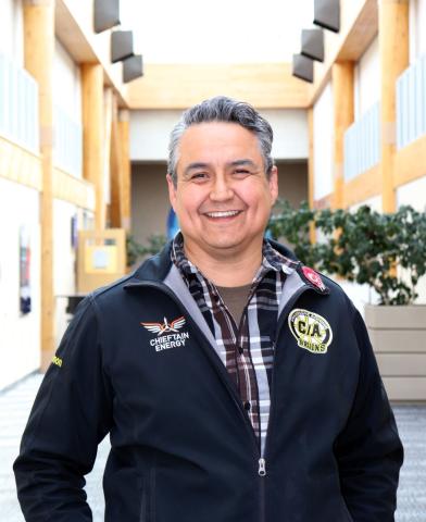First Nations man stands in hallway smiling
