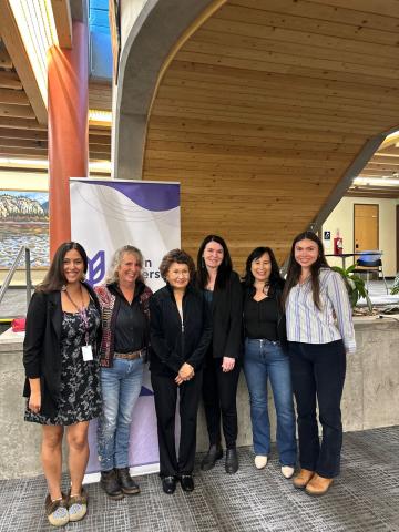 six women pose in front of a yukon university banner as a celebration