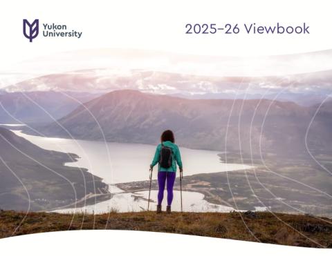 A woman carrying hiking poles overlooking a lake in the mountains. Cover of the 2025-26 Yukon University Viewbook.