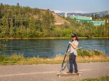 Joel Brennan rides a longboard along the waterfront trail using the SUPStick he invented