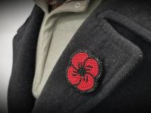 A beaded poppy on the lapel of a charcoal coloured coat