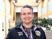First Nations man stands in hallway smiling