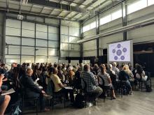A large room full of people facing a man giving presentation.